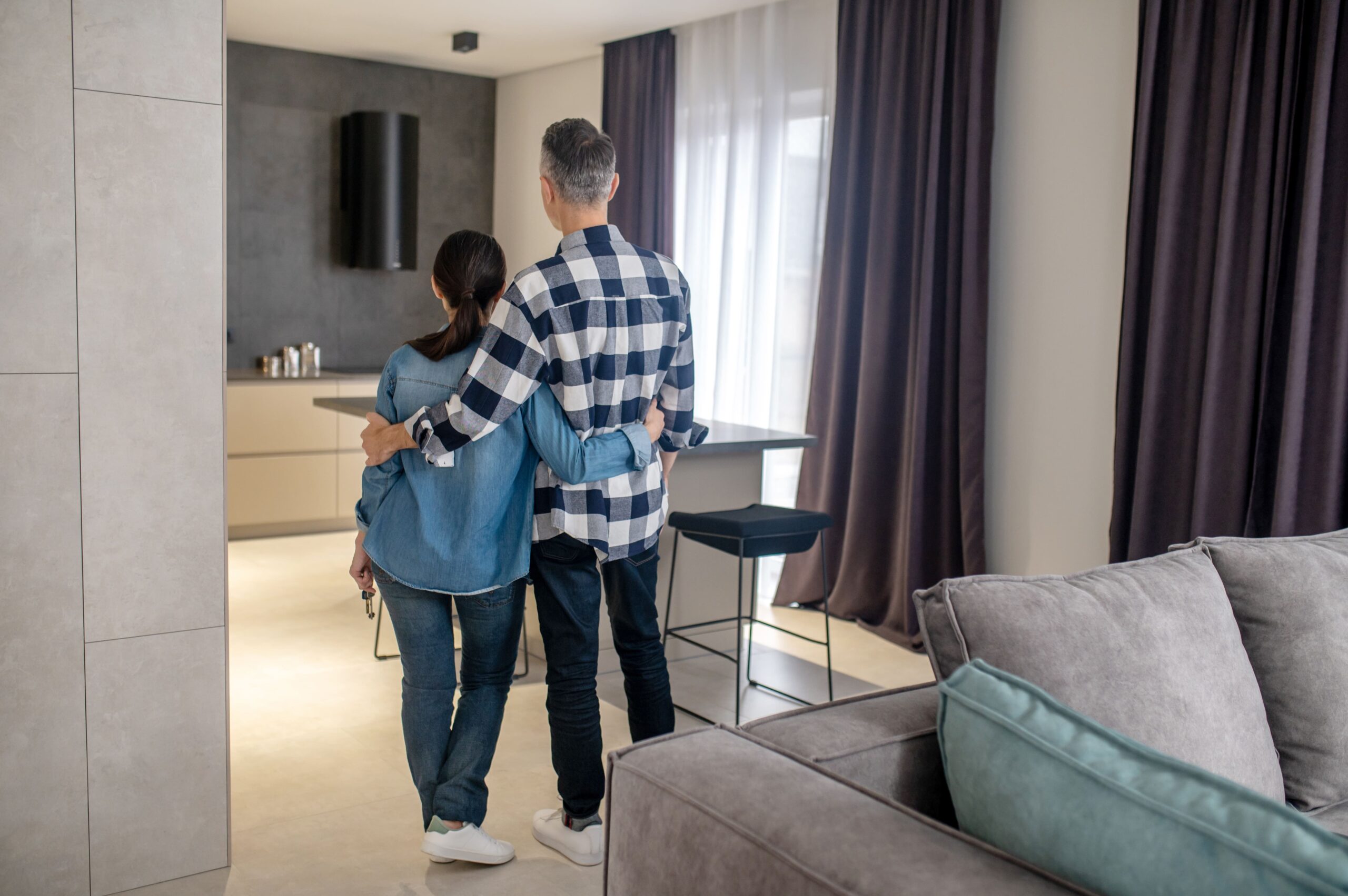 new-house-back-view-of-man-and-woman-holding-keys-in-hand-standing-in-new-modern-house